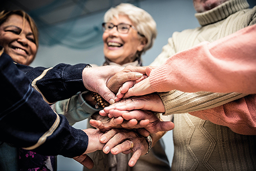 Foto de tres personas de la tercera edad poniendo mano sobre mano